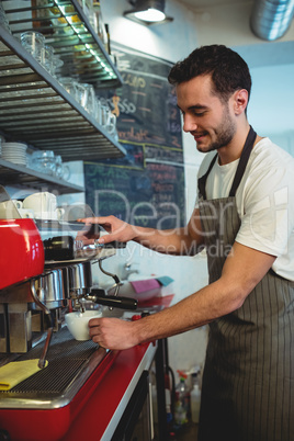 Happy barista using espresso maker at cafe