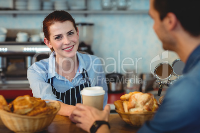 Portrait of happy barista giving coffee to customer at cafe