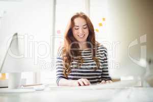 Happy businesswoman working at desk in creative office