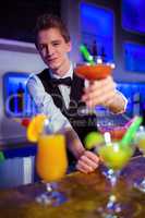 Portrait of smiling bartender holding cocktail glass