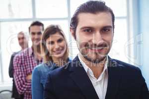 Smiling businessman with colleagues standing in row
