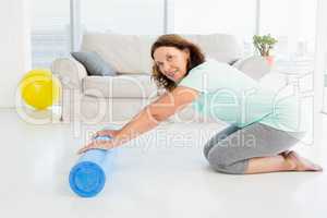 Portrait of smiling mature woman rolling exercise mat