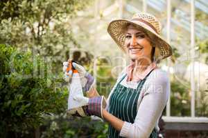 Happy female gardener spraying water on plants