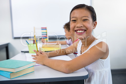 Happy girl studying at desk in in classroom