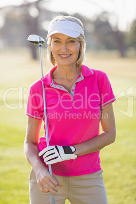 Portrait of confident mature golfer woman carrying golf club