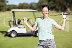 Portrait of cheerful woman carrying golf club