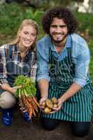 Gardeners holding harvested carrots and potatoes