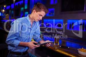 Young man using digital tablet at bar counter
