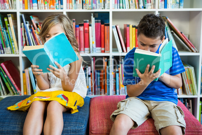 Students reading books while sitting in school library