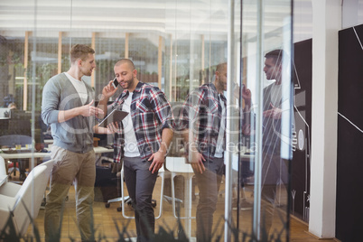 Colleague discussing while businessman talking on phone