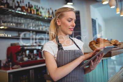 Female barista using digital tablet at coffee shop