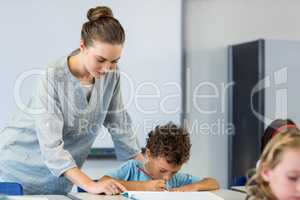 Teacher looking at student writing on book