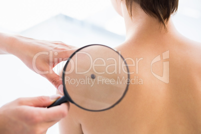 Cropped image of doctor checking patient using magnifying glass