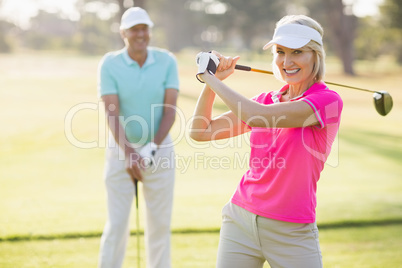 Portrait of confident mature woman carrying golf club by man