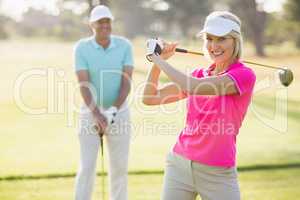 Portrait of confident mature woman carrying golf club by man