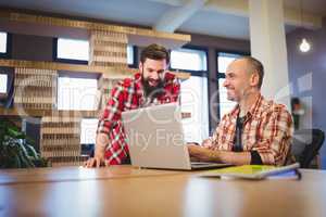Creative male coworkers discussing over laptop
