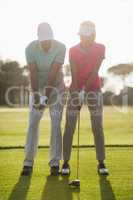 Full length of mature male golfer teaching woman
