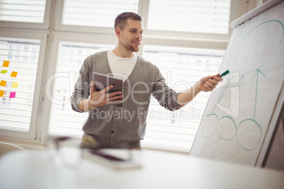 Businessman holding digital tablet while giving presentation in