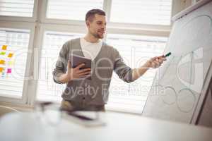 Businessman holding digital tablet while giving presentation in