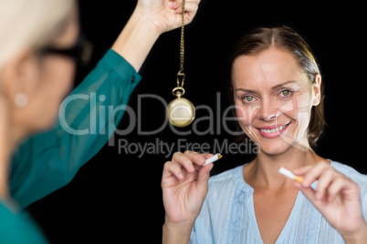 Hypnotherapist holding pendulum by patient