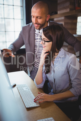 Businessman explaining female coworker over computer