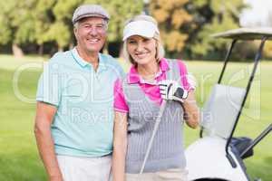 Happy mature couple standing at golf course