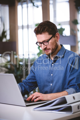 Confident executive working on laptop at creative office