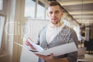 Portrait of businessman holding file at creative office