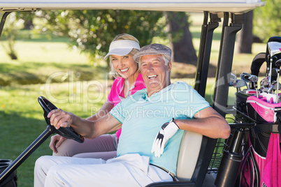 Cheerful mature golfer couple sitting in golf buggy