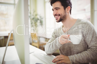 Businessman holding coffee cup while working at desk Businessman holding coffee cup while working at desk