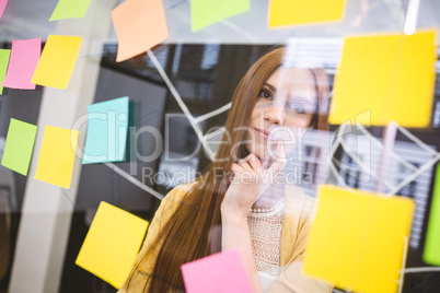 Thoughtful businesswoman looking on sticky notes