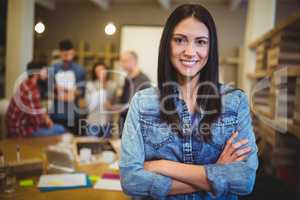 Businesswoman by table with colleagues in background