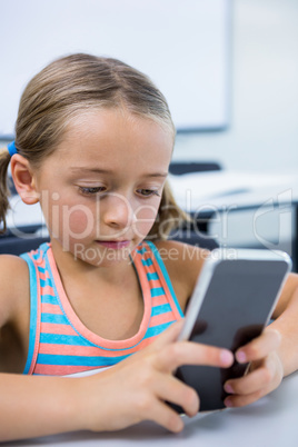 Elementary girl using mobile phone in classroom