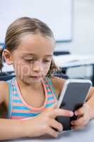 Elementary girl using mobile phone in classroom