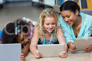 Smiling teacher with girls using digital tablets