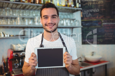 Portrait of confident barista holding blank chalkboard