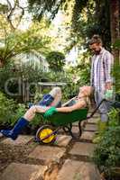 Happy colleagues enjoying with wheelbarrow in garden