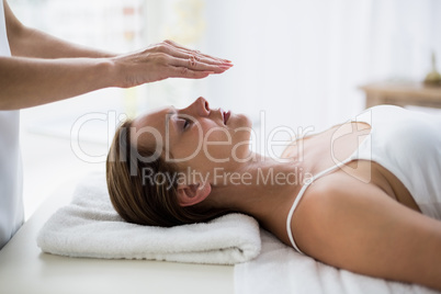 Cropped hands of therapist performing reiki on woman