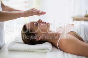 Cropped hands of therapist performing reiki on woman