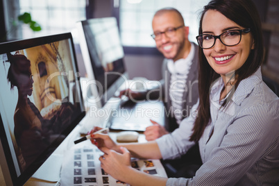 Happy creative coworkers sitting at computer desk