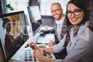 Happy creative coworkers sitting at computer desk