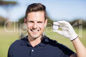 Portrait of cheerful young man showing golf ball