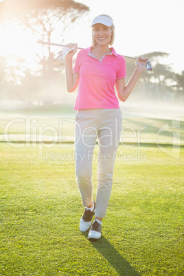 Portrait of cheerful woman carrying golf club