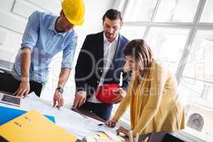 Tilt image of business people looking at blueprint