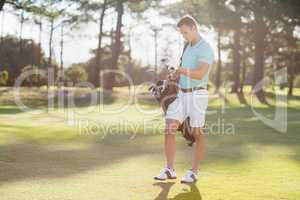 Full length of young man carrying golf bag