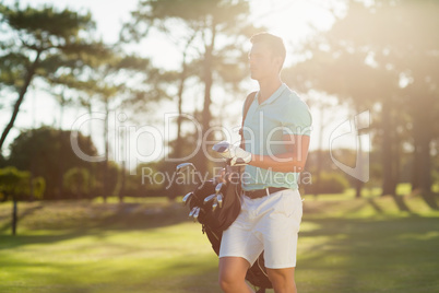 Young man carrying golf bag