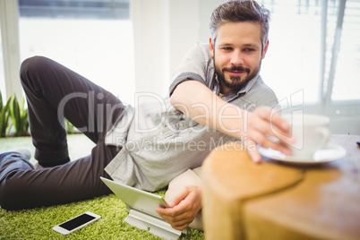 Businessman taking coffee cup while relaxing at creative office