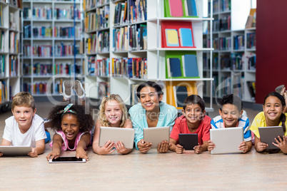 Smiling teacher with students using digital tablets