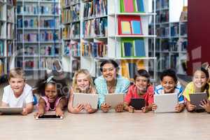 Smiling teacher with students using digital tablets