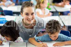 Portrait of happy female teacher helping schoolchildren